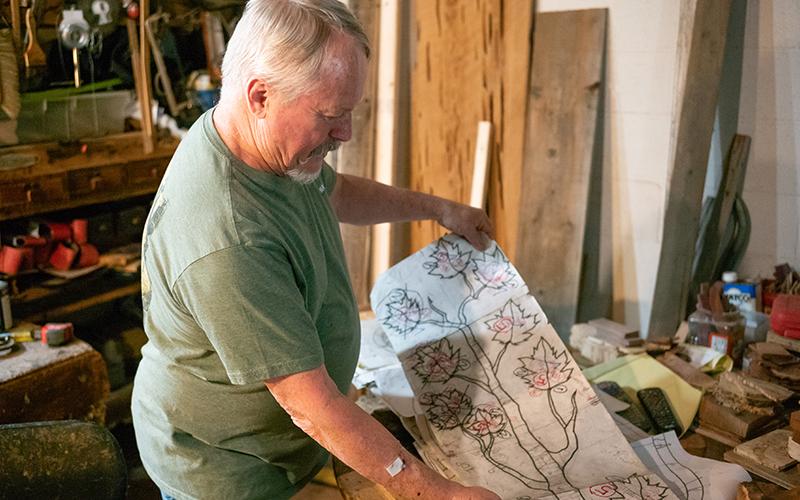 Banks shows his hand-drawn designs of intricate wood layouts that are used in table making. ZACH TAYLOR /Staff