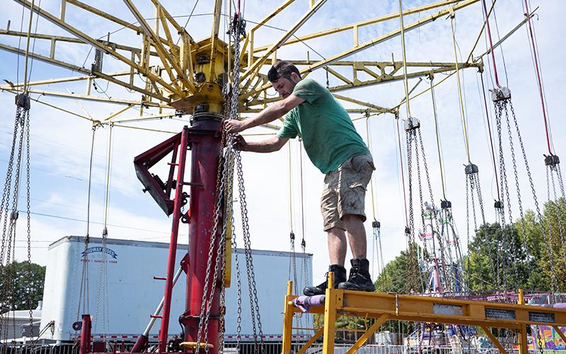 Tim McCoy adjusts the chains on the swing ride before testing its functionality. ZACH TAYLOR/Staff
