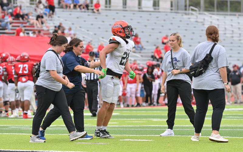Head Athletic Trainer London Addison (navy shirt) and AT students from UNG and Piedmont help Raider football player Landyn Savage off the field during a game this season. TOM ASKEW/Special