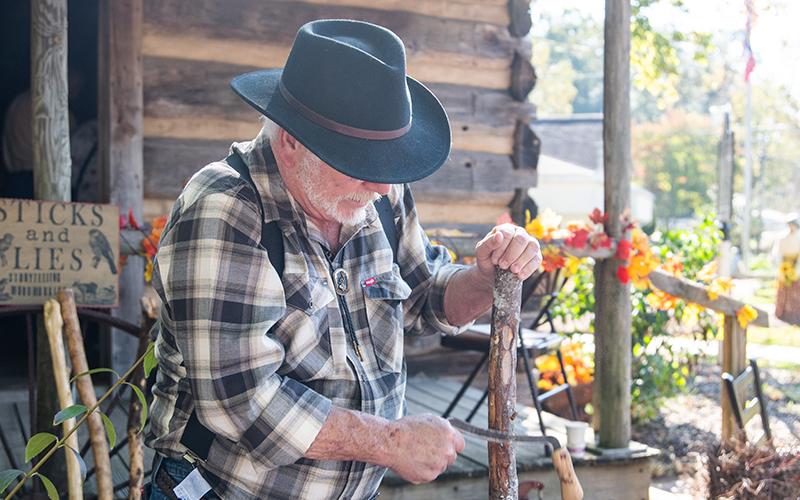 Jeff Blackwell carves into a cane during Clarkesville History Harvest on Saturday. His passion is woodworking, which he says brings him peace. ZACH TAYLOR/Staff