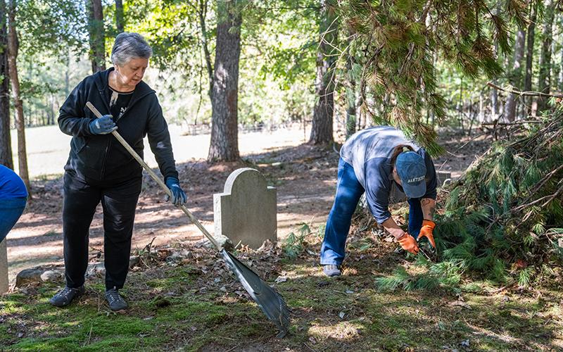 Gwen Ivester and Lynn McCollum work to clean around the grave sites on Saturday. ZACH TAYLOR/Staff