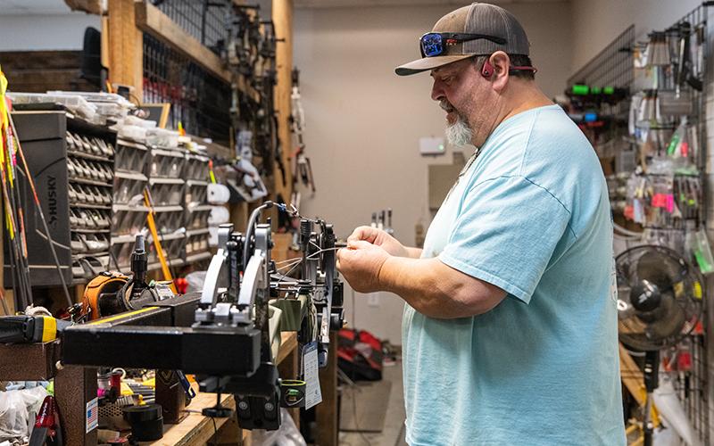 Greg Hope tunes a new bow in a bow press for a customer during a workday on Wednesday. Hope is one of two brothers who manage the archery, gun and shooting range business in Demorest. ZACH TAYLOR/Staff