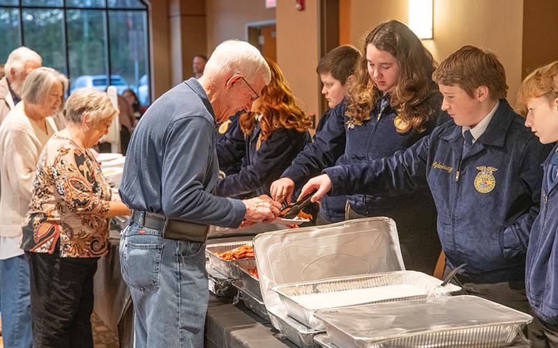 Farm Bureau Board Member Danny Brooks is served a hot meal from Crossroads Cafe by Habersham County FFA’s Aydan Savage. ZACH TAYLOR/Staff