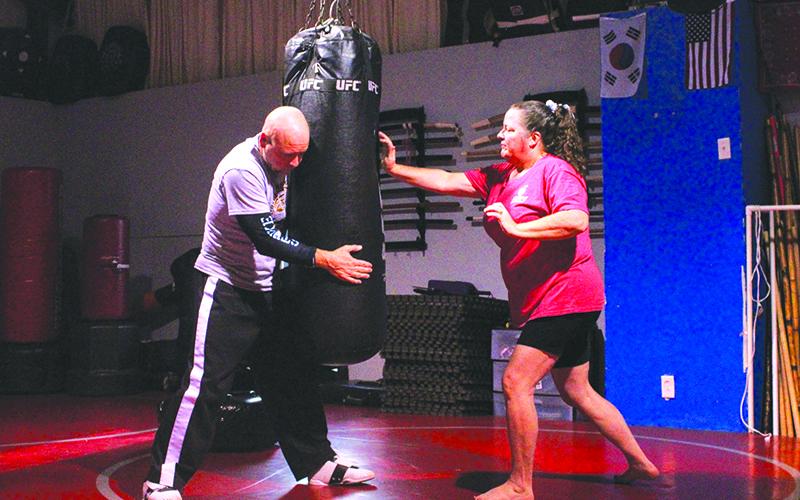 Bobby Popham (left) holds a punching bag while Ellie Van Doornum (right) strikes with her right palm against the tough fabric. HANNAH CAUDELL/Staff