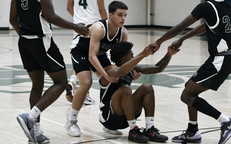 Neyo Bain is helped to his feet by teammates after missing a buzzer beater at the end of the 1st half Saturday. LANG STOREY/Staff
