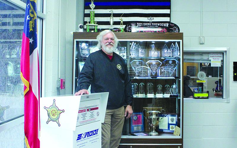 Sheriff Joey Terrell stands in front of the trophies detailing the police department’s accolades. HANNAH CAUDELL/Staff