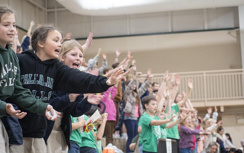 TFS Students Allegra Perry, Piper Prince and Riley McCracken cheer on the Piedmont Lions and reach to catch pom-poms and bouncy balls given away at the game. JULIANNE AKERS/Staff