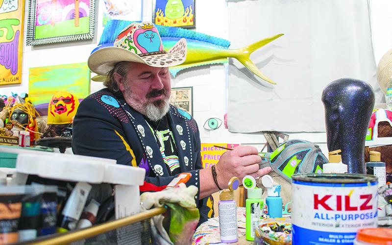 Chris Allison paints a hat at his art studio in Mt. Airy. JULIANNE AKERS/Staff