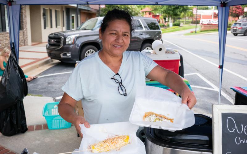The City of Cornelia hosted many events for Hispanic and Latin culture over the past few years that helped it earn one of three 2025 Visionary City Awards by the Georgian Municipal Association in the small city category. Pictured here, Orlanda Marroquin holds an elote and a fresh taco at a festival in downtown Cornelia in July and runs a small business selling Hispanic foods and treats. ZACH TAYLOR/Staff