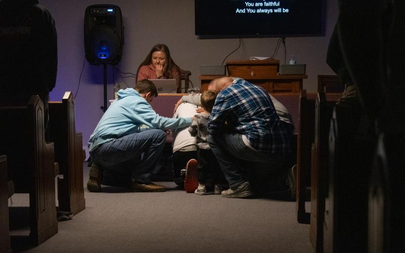 Some men of the church come before the altar to pray, and their fellow church goers follow to lay hands in support.  HANNAH CAUDELL/Staff
