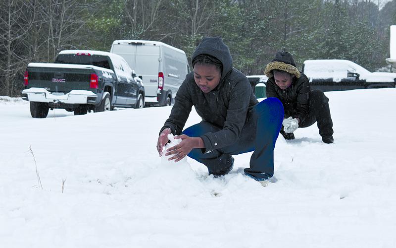 Miel Ngandu and Graciel Ngandu work on building snowmen in their family’s yard Friday afternoon. SAMANTHA SINCLAIR/Staff