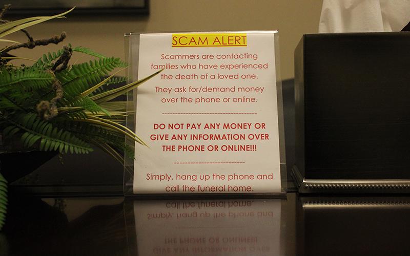 A scam alert sits in the conference room at McGahee-Griffin &amp; Stewart Funeral Home, meant to warn incoming families of the scam calls that have been plaguing the North Georgia area for a little over a year. HANNAH CAUDELL/Staff
