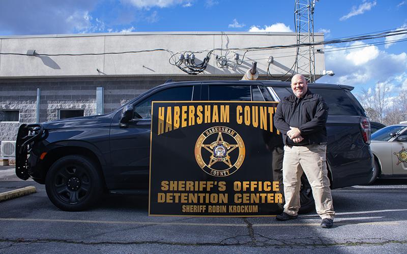 Robin Krockum is the new sheriff in town as of Jan. 1, 2025. Krockum stands before a police vehicle with the new sheriff office sign, his name emblazoned at the bottom. HANNAH CAUDELL/Staff
