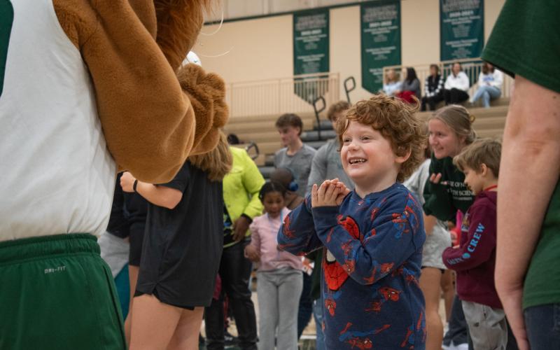 Elementary schooler Ben Hunter smiles with enthusiasm as he claps his hands with Piedmont’s lion mascot. HANNAH CAUDELL/Staff