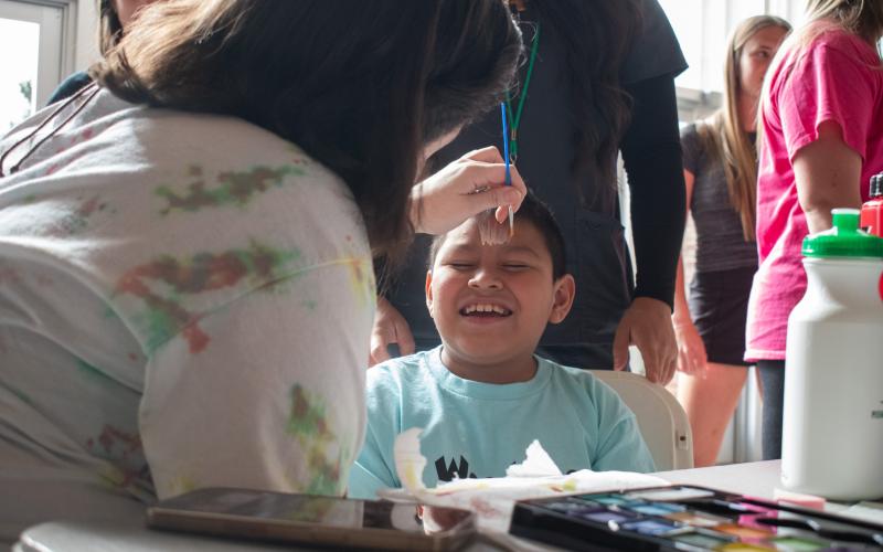 Mateo Mateo-Diego gets into the Lion Pride spirit while a volunteer paints his face to resemble the cat’s signature mane. HANNAH CAUDELL/Staff