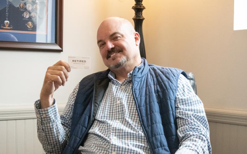 HANNAH CAUDELL/Staff Superintendent Matthew Cooper holds up a new kind of business card, one that suggests he won’t be available anytime soon after Thursday. Cooper has served the Habersham County School System for 13 years as superintendent, the longest-acting superintendent in the school system’s history. HANNAH CAUDELL/Staff