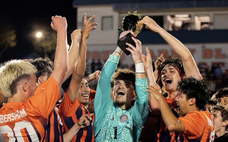 Surrounded by teammates, HCHS keeper Everett Rudeseal hoists the region trophy after the Raiders clinched another championship Thursday night. HABERSHAM SOCCER