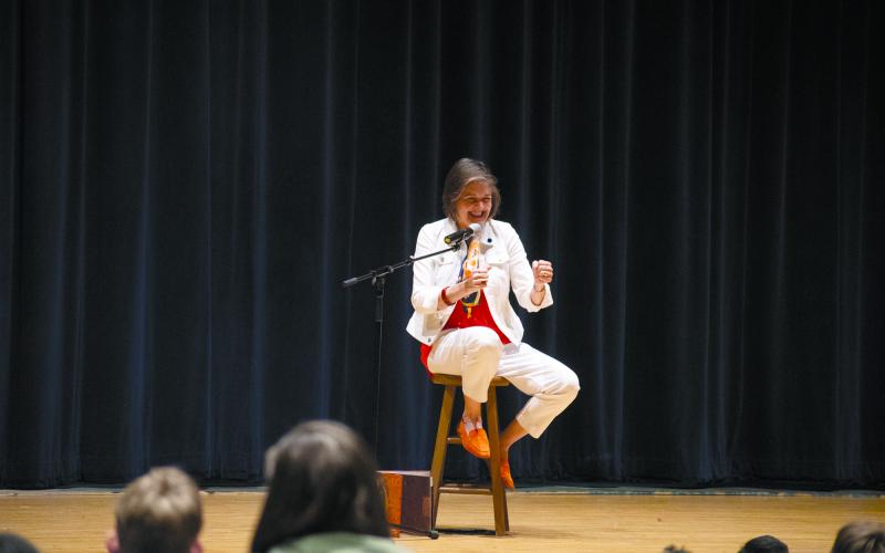 Carmen Agra Deedy sits on the stage of the Habersham Central Performing Arts Center, miming as she tells the story of Juan Bobo, a Spanish wise-fool’s tale that has the students in the audience spellbound. HANNAH CAUDELL/Staff