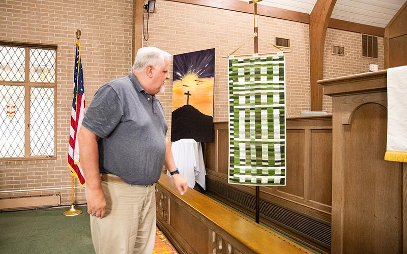 Pastor Randy Kanipe shows the weaving banner in the sanctuary. The weaving banner is a display of more than 130 pieces of fabric brought by an individual from the now mixed congregation, showcasing unity as one church body. ZACH TAYLOR/Staff