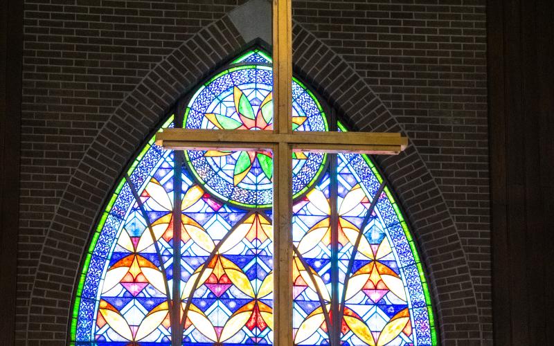 The cross stands before a colorful stained glass window in the sanctuary – a symbol of faith for the two United Methodist congregations that merged to form one. ZACH TAYLOR/Staff