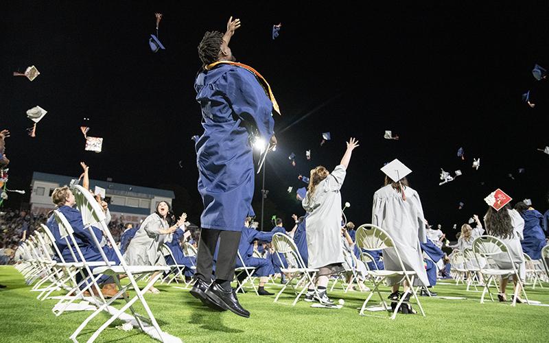 Kendall Respress leaps into the air as he throws his graduation cap with other graduates. ZACH TAYLOR/Staff