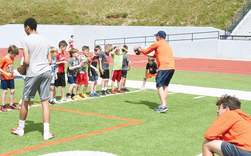 Coach Tate Gailey instructs campers in a wide receiver drill in 2023.