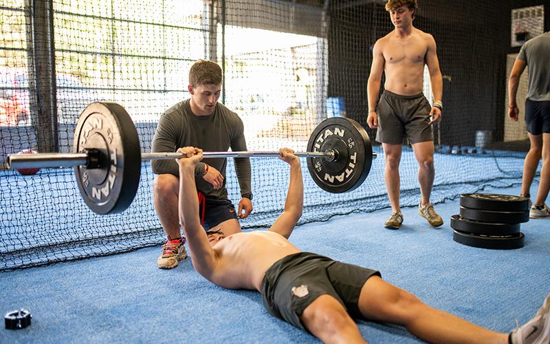 Garrett Kinsey spots Noah Harkins as he does floor press with a bar, as the gym area was closed off for the final touches on the air conditioning system on Monday. ZACH TAYLOR/Staff