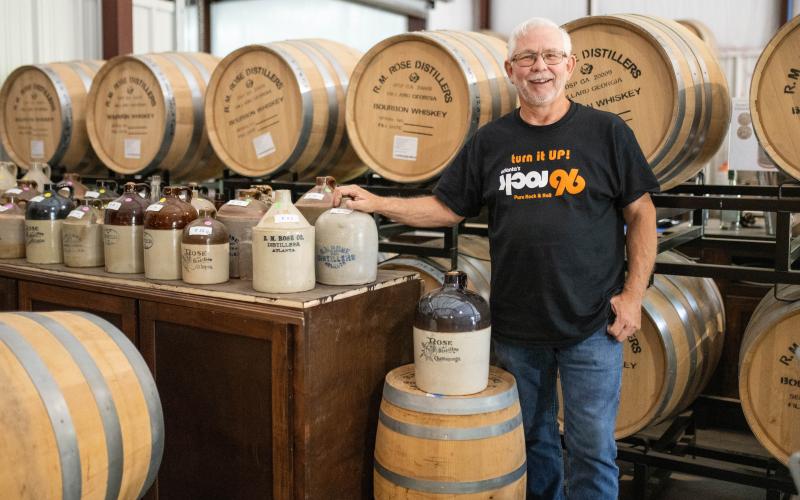 Owner Andy Sudderth stands next to barrels full of whiskey in the new distillery in Mt. Airy, his hand resting on a ceramic jug from the R.M. Rose Distillery in Atlanta in the late 1800s. ZACH TAYLOR/Staff