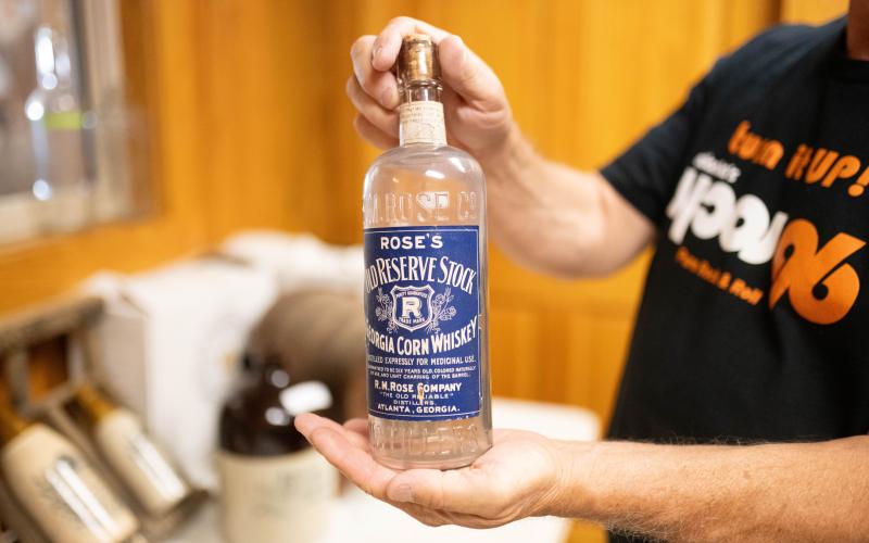 Andy Sudderth holds a more than 100-year-old bottle with label intact from the original R.M. Rose Distillery. ZACH TAYLOR/Staff