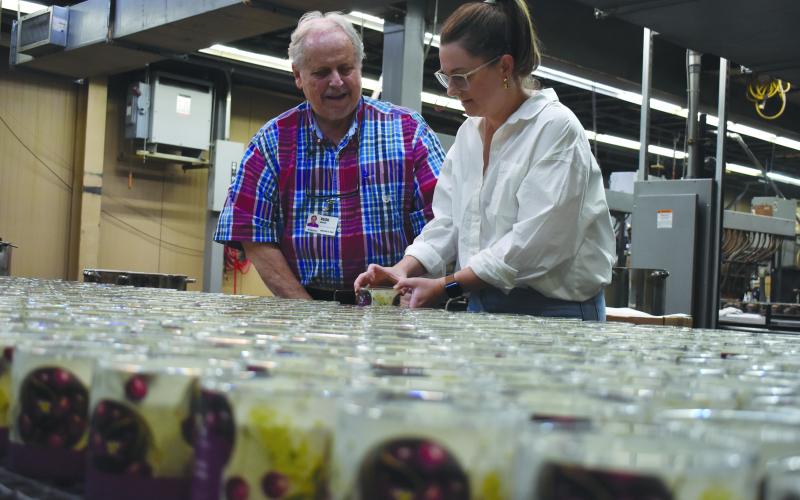 GlobalTech Owner Rush Mauney and his daughter and GlobalTech Director of Marketing and Communications Jessamine Cantey take a look Goose Creek Black Cherry candles coming down the production line. They are celebrating 30 years of the candle business with employees. Samantha Sinclair/Staff