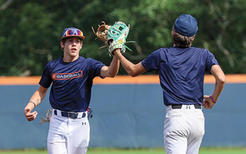 Habersham Central High School’s Tanner Yarbrough and Asa Popham tap gloves during the orange and blue series on Thursday, June 19 at Raider Park. The orange team won both games. (Landen Todd/Staff)