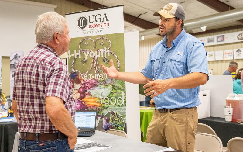 Nathan Eason (right) speaks with a farmer at the North Georgia Ag Expo about the things the UGA Extension does for the state’s agricultural interests, including education. (Zach Taylor/Staff)