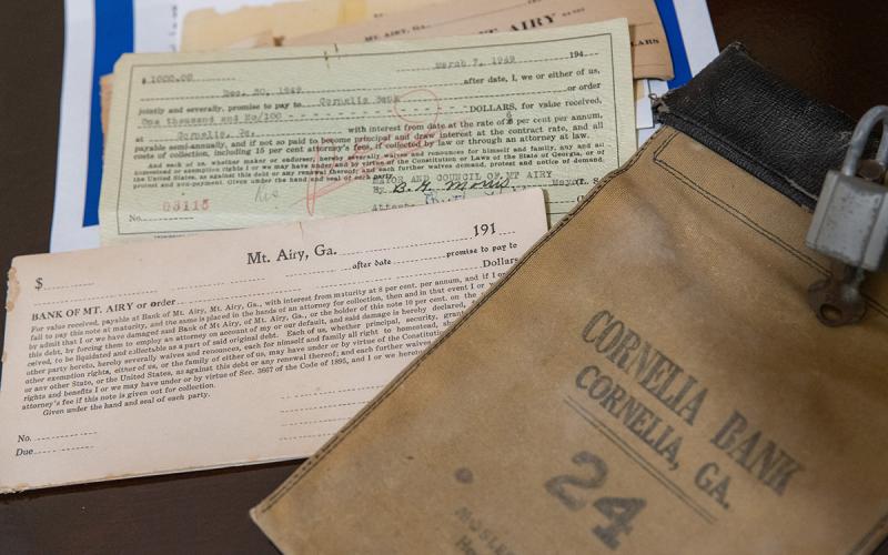 Old ledgers, checkbooks and loan cards from the Bank of Mt. Airy sit next to a bank bag from Cornelia Bank from around the same era. Banking artifacts in the Mt. Airy museum date back to 1917.  (Zach Taylor/Staff)