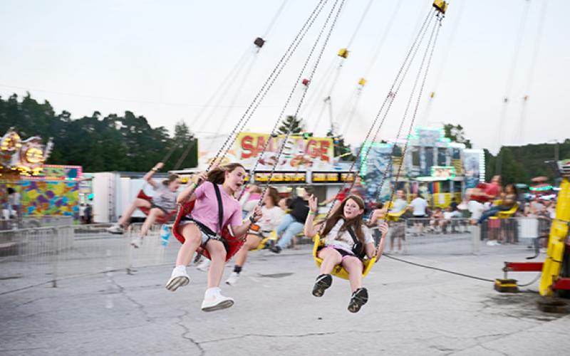 Makenna Pirkle (left) and Stella Nash (right) take a spin on the swing ride at the Chattacoochee Mountain Fair in 2023. (Zach Taylor/Staff)