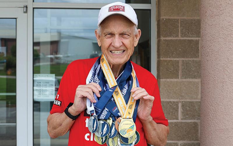 Long time runner David Turner poses for a portrait with all of his medals he has won over the years at The Northeast Georgian on Aug. 12. (Landen Todd/Staff)