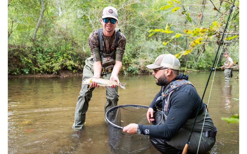 Jackson Savage holds a fish after being guided by Seth Underwood during the fly fishing festival on Sunday. (Zach Taylor/Staff)