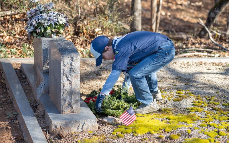Cub Scout Gabriel Nichols lays a wreath during the ceremony on Saturday at Demorest City Cemetery. (Zach Taylor/Staff)