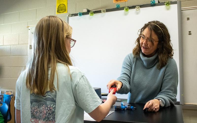Discovery Teacher Hannah DeMore hands a lock to one of her students, who wishes to see if she broke the code during a class exercise. (Hannah Caudell/Staff)
