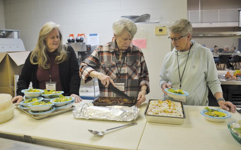 Kitchen volunteers Kim Finley, Claudia Jessup and Tina Hatcher prepare meals for the guests at the warming center Monday night. (Samantha Sinclair/Staff)