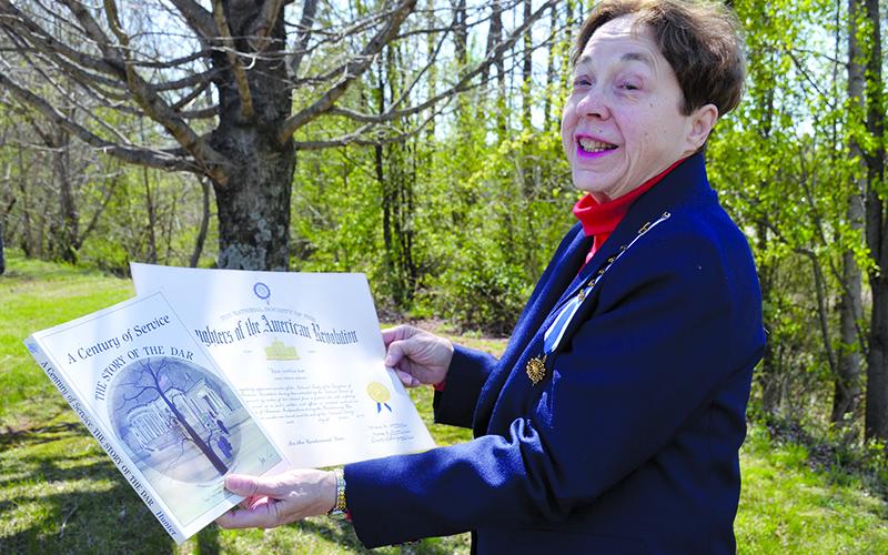 Delores Anderson shows her Daughters of the American Revolution membership certificate and her copy of A Century of Service: The Story of DAR. The year she joined was the centennial year of the society. Samantha Sinclair/Staff