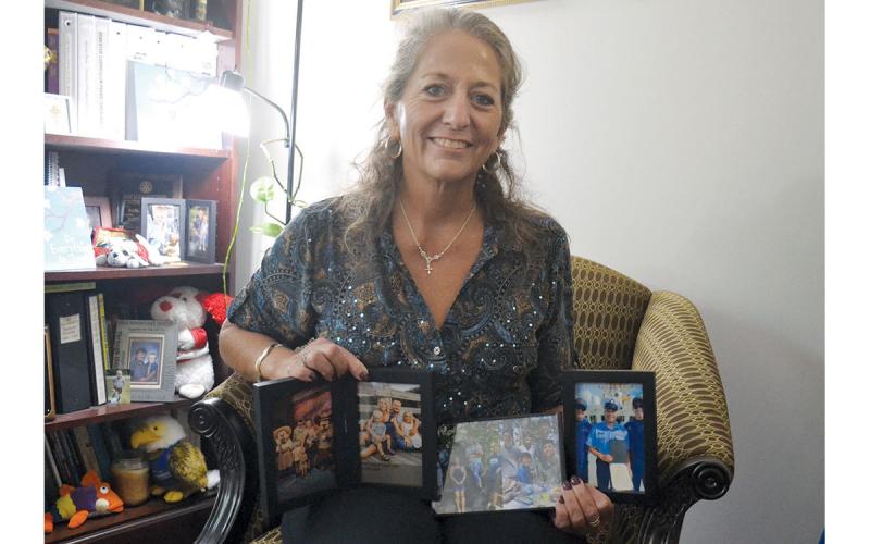 Dr. Fran Chastain shows some of her favorite photos of her 13 children and nine grandchildren in her office at North Georgia Technical College. She has 13 children, 11 of which were adopted. (Samantha Sinclair/Staff)