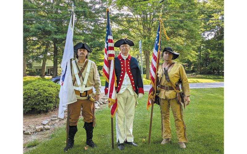 Brent Smith (left) holds the America 250 flag alongside Sons of the American Revolution Joseph Habersham Chapter member Dr. Ed Hendricks (middle) and Lyman Hall Chapter member David Lowden at the Mountain Laurel Festival Parade in Clarkesville. Smith tried to wear what he believed his grandfather would have worn in the war. (Submitted)
