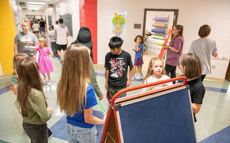 Students and parents refer to a board of names to determine where to meet teachers for the beginning of the school year’s open house last year. (File)