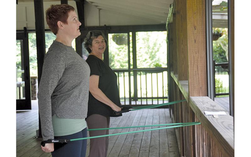 Juanita Broom, right, smiles at Christine Hopkinson as they do a resistance band workout during the wellness retreat at Glen-Ella Springs Inn and Restaurant. (Samantha Sinclair/Staff)