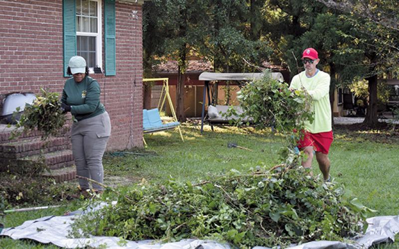 From left, Cristina Simmons and Cornelia City Manager Dee Anderson help clean and pick up trimmed branches at a home in the city during the Helping Hands event on Saturday. (Noah Ansley/Staff)