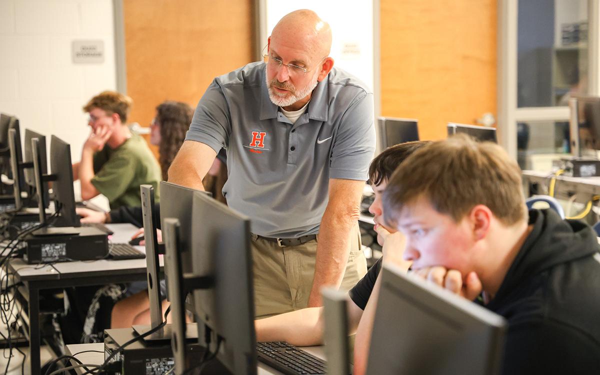 Jim Mitchell, a math and computer science teacher at Habersham Central High School, helps Tristan Evans with an assignment in the high school’s newest computer science pathway class. (Hannah Caudell/Staff)