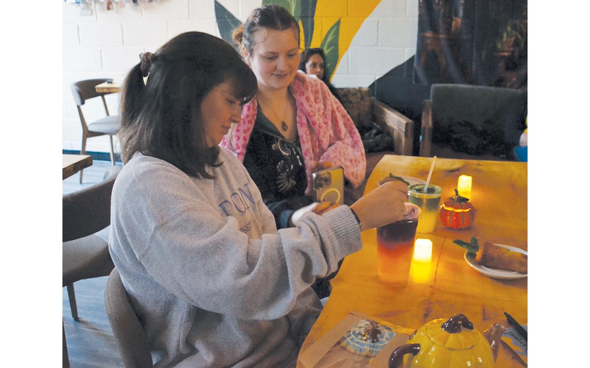 Hannah Conley gets ready to try her Poly Juice drink as Faith Ross takes photos of the Potter-themed goodies placed before them as “Harry Potter and The Chamber of Secrets” plays. (Samantha Sinclair/Staff)