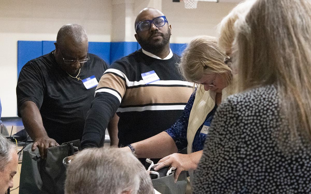 Shady Grove Baptist Church Pastor Sherrod Aiken, along with other volunteers, prays over the cots the Matthew 25 Alliance will use for the warming center as winter approaches. (Hannah Caudell/Staff)