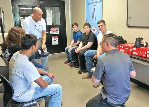 Habersham Central High School students in the dual-degree welding program at North Georgia Technical College were fitted Thursday morning for their safety boots. Students shown sitting in a circle, left to right, are 10th-grader Gabe Blackburn, 12th-grader Katie McCoy, 11th-grader Joshua Brock, 11th-grader Adrian Frankum and 10th-grader Drew Maneg. (Photo/CHAMIAN CRUZ)