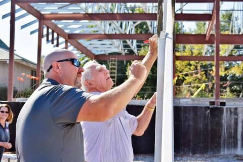 Cornelia City Manager Donald Anderson, left, and Cornelia Mayor James C. “J.C.” Irby ink their signatures on the final beam before it’s placed atop the city’s new municipal complex during a topping-out ceremony Friday, Sept. 6, at the site. (Photo/CHAMIAN CRUZ)